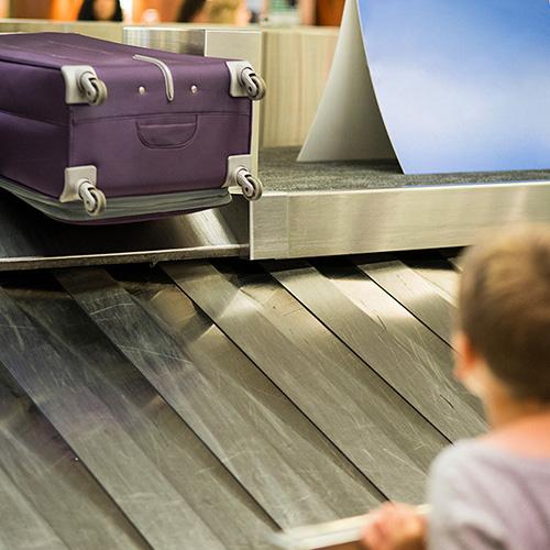 Young boy waiting for his bag to come up the conveyor belt at baggage claim