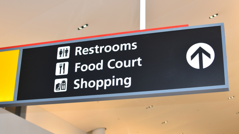 Photograph of an overhead wayfinding sign leading passengers to shopping and restaurants at BWI Marshall Airport.