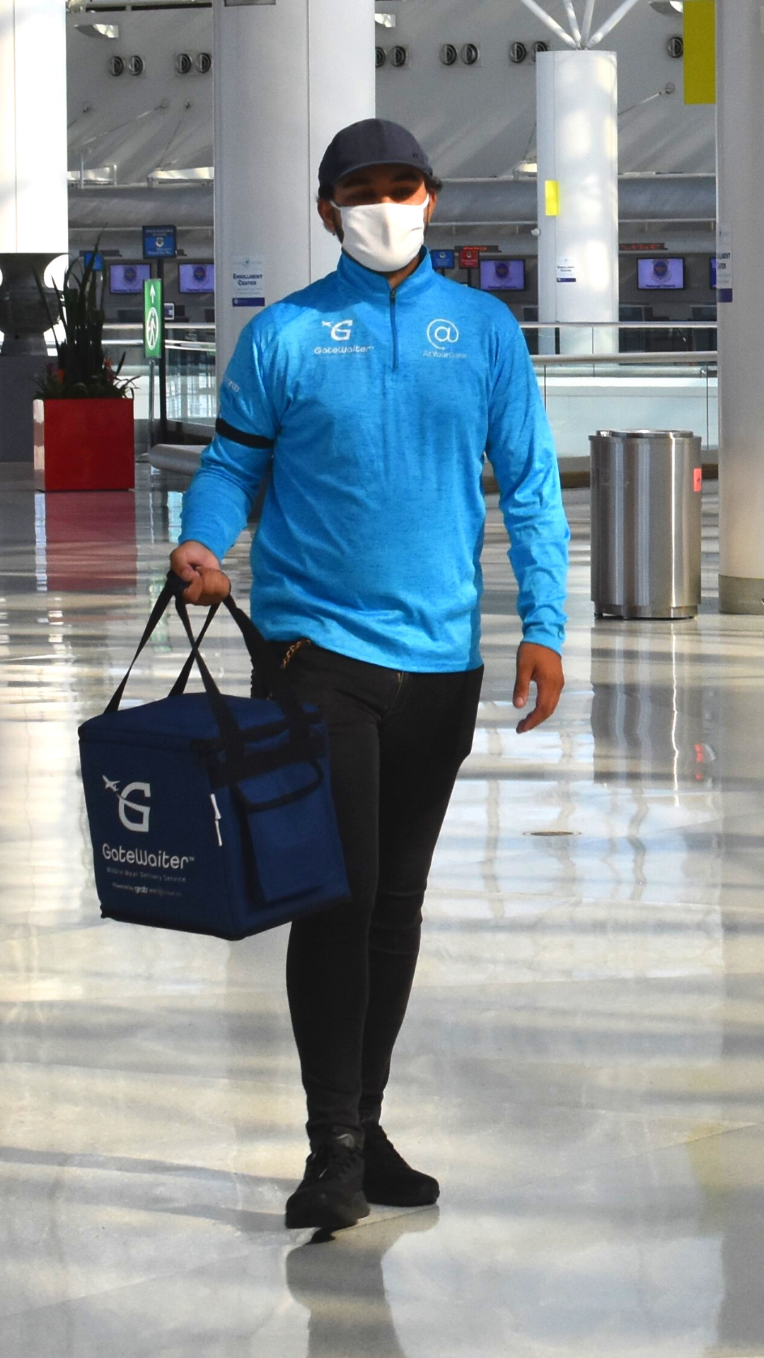 Photograph of GateWaiter staffer carrying a delivery bag through the BWI Marshall Airport terminal.