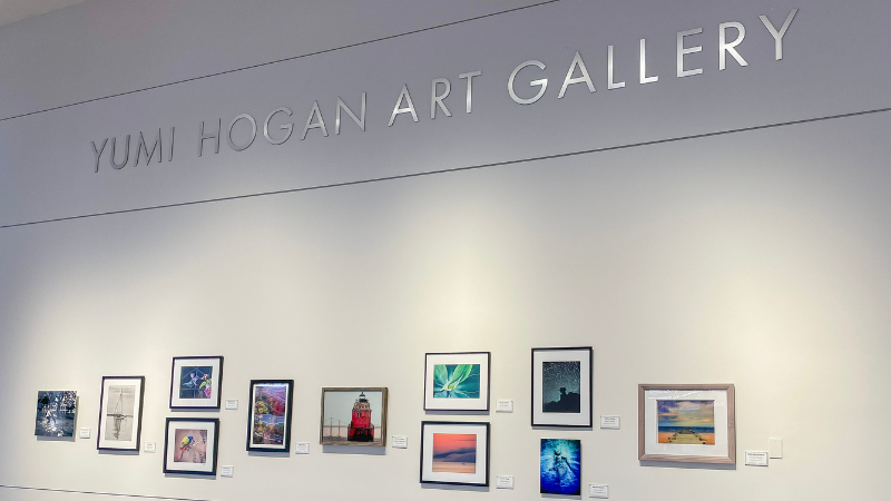 Several photographs on display plus an art gallery name plate at the Yumi Hogan International Art Gallery at BWI Marshall Airport