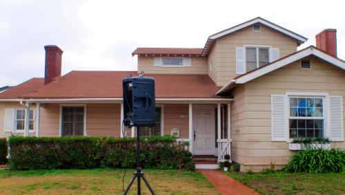 Photo of a home with a noise measuring equipment in the front yard.