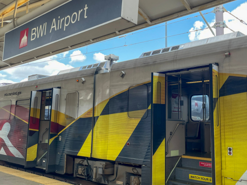 Photo of an MTA Light Rail adorned with Maryland flag-themed exterior graphics stopped at the platform at BWI Marshall Airport.