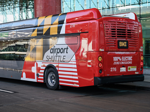 Photo of the rear half of a BWI Marshall Airport parking shuttle on the Departures Level roadway in front of the terminal.