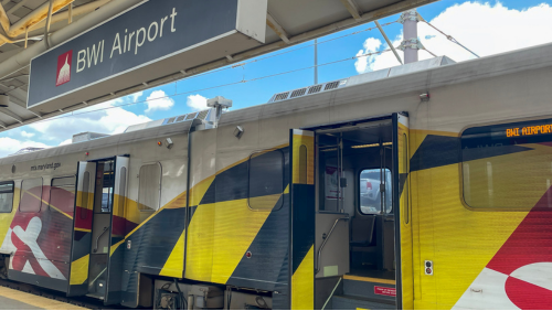 Photo of an MTA Light Rail adorned with Maryland flag-themed exterior graphics stopped at the platform at BWI Marshall Airport.