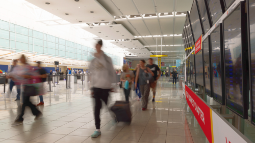 Photo of passengers walking past a bank of flight information screens at BWI Thurgood Marshall Airport.