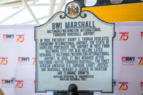 Photo of a roadside historical marker honoring BWI Thurgood Marshall Airport's 75-year history during an unveiling event at the airport.