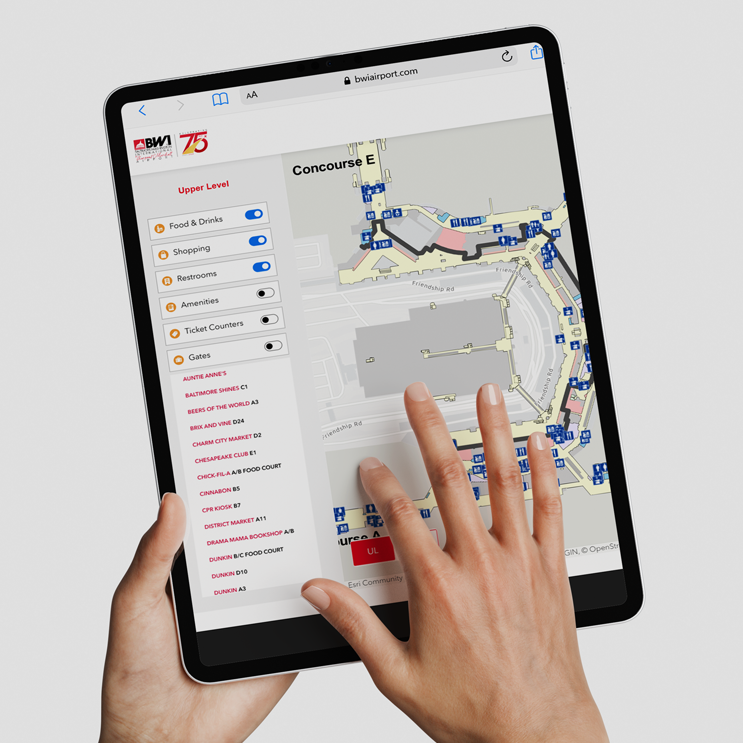 Graphic rendering showing hands holding a tablet showing the interactive wayfinding map on BWIairport.com.
