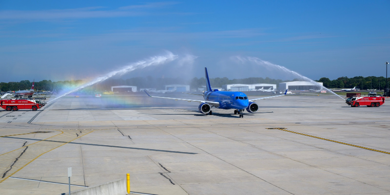 A Breeze Airways aircraft taxis beneath a water arch from the BWI Marshall Airport Fire and Rescue Department.